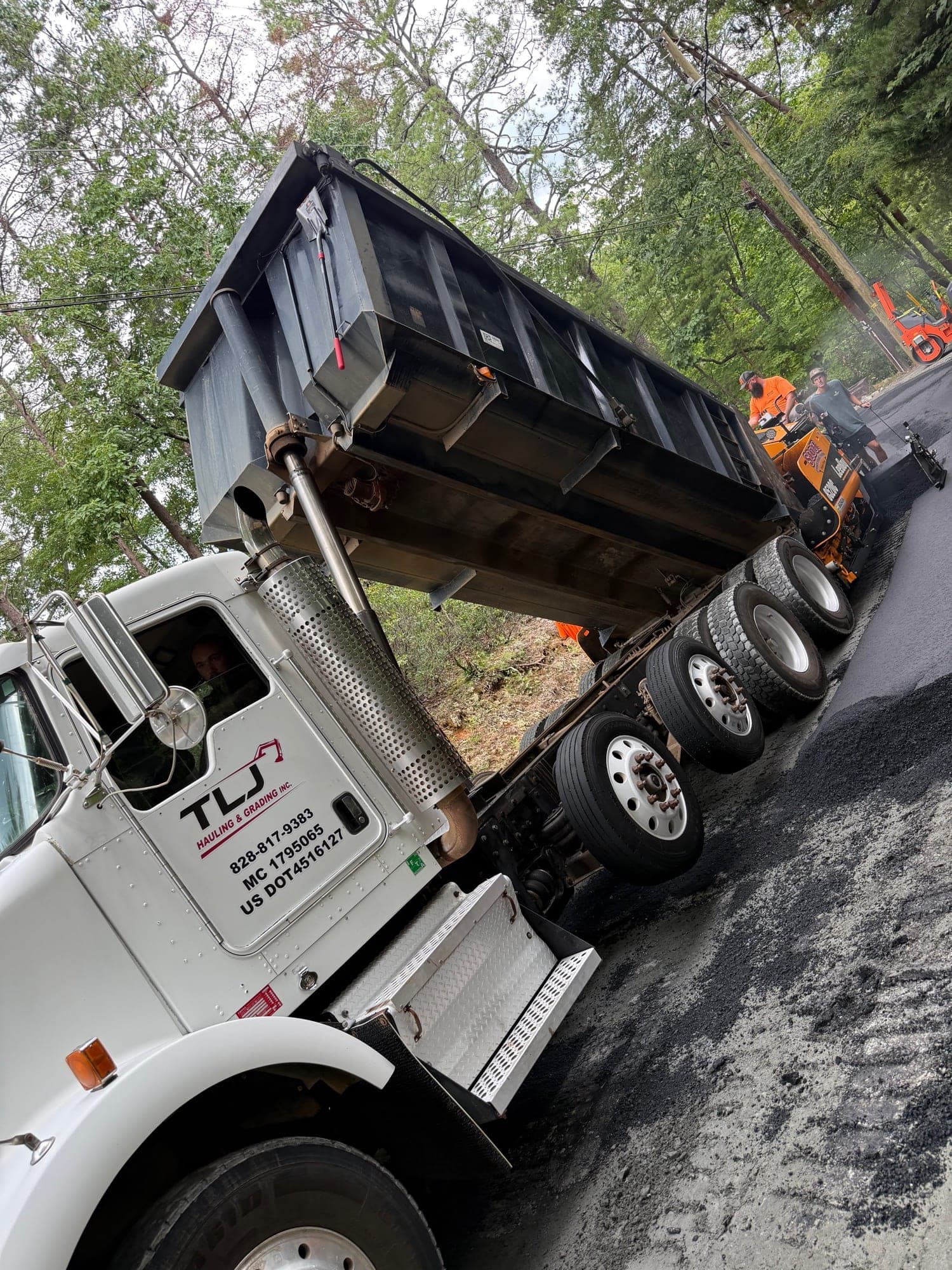 TLJ dump truck dumping hot mix asphalt into a paver