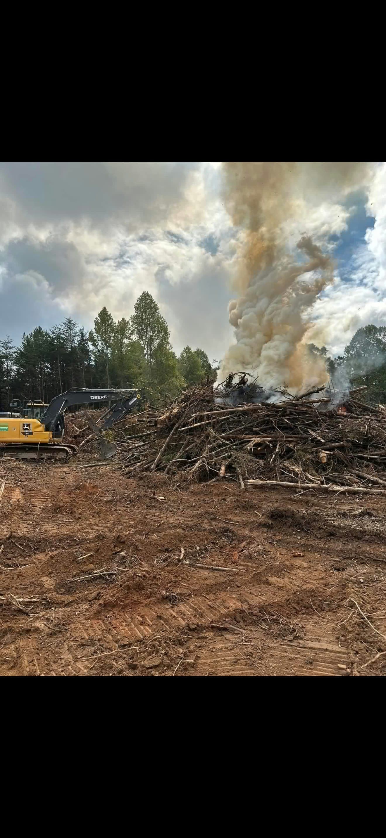 Excavator on a land clearing burn pile