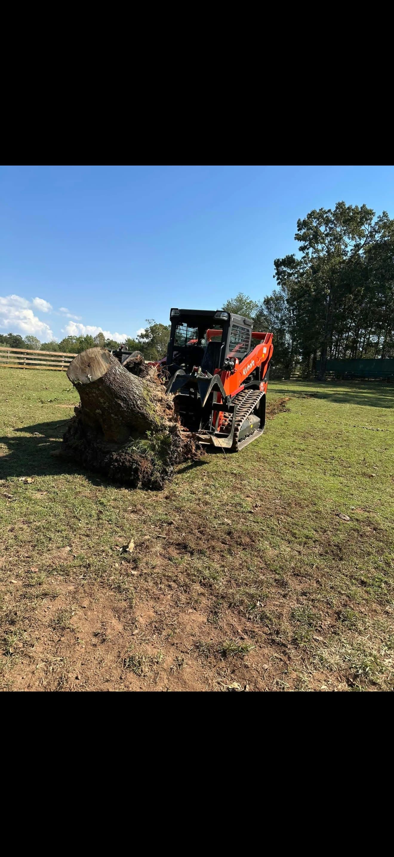 Track loader pulling a stump with a grapple