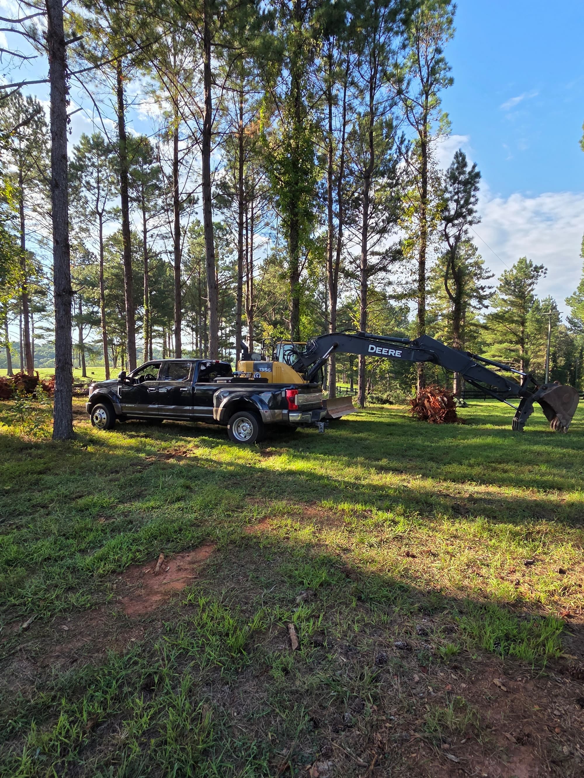 Pickup and excavator on a wooded clearing job