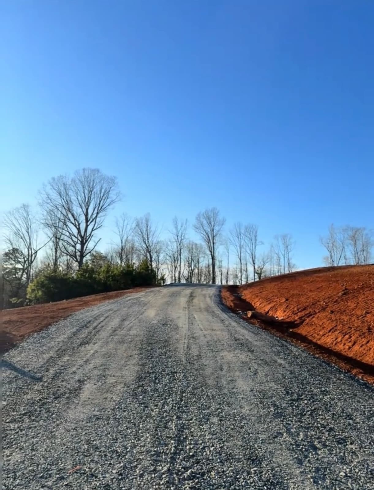 Newly spread gravel driveway climbing a graded bank