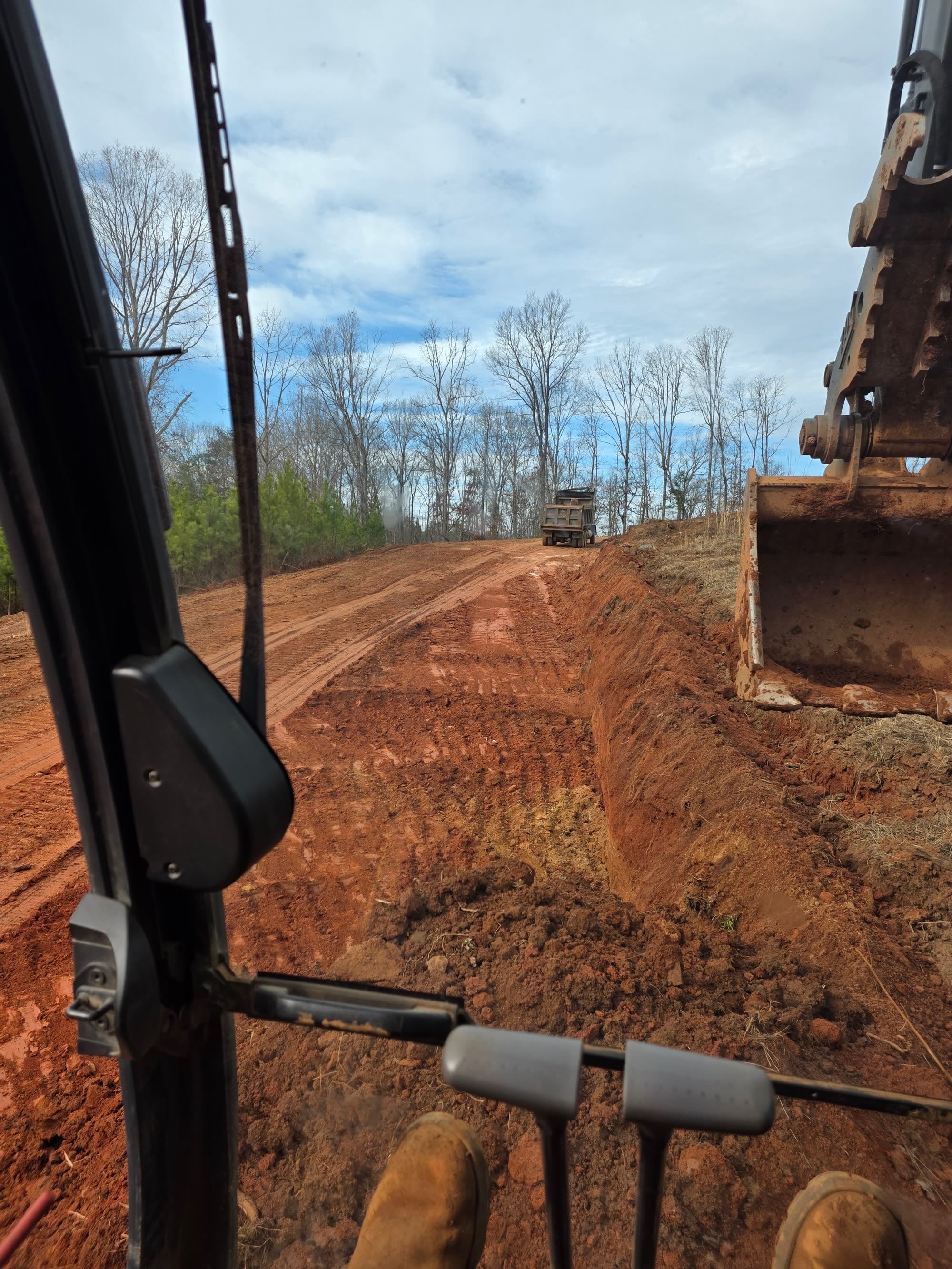 View from the excavator cab across a graded site