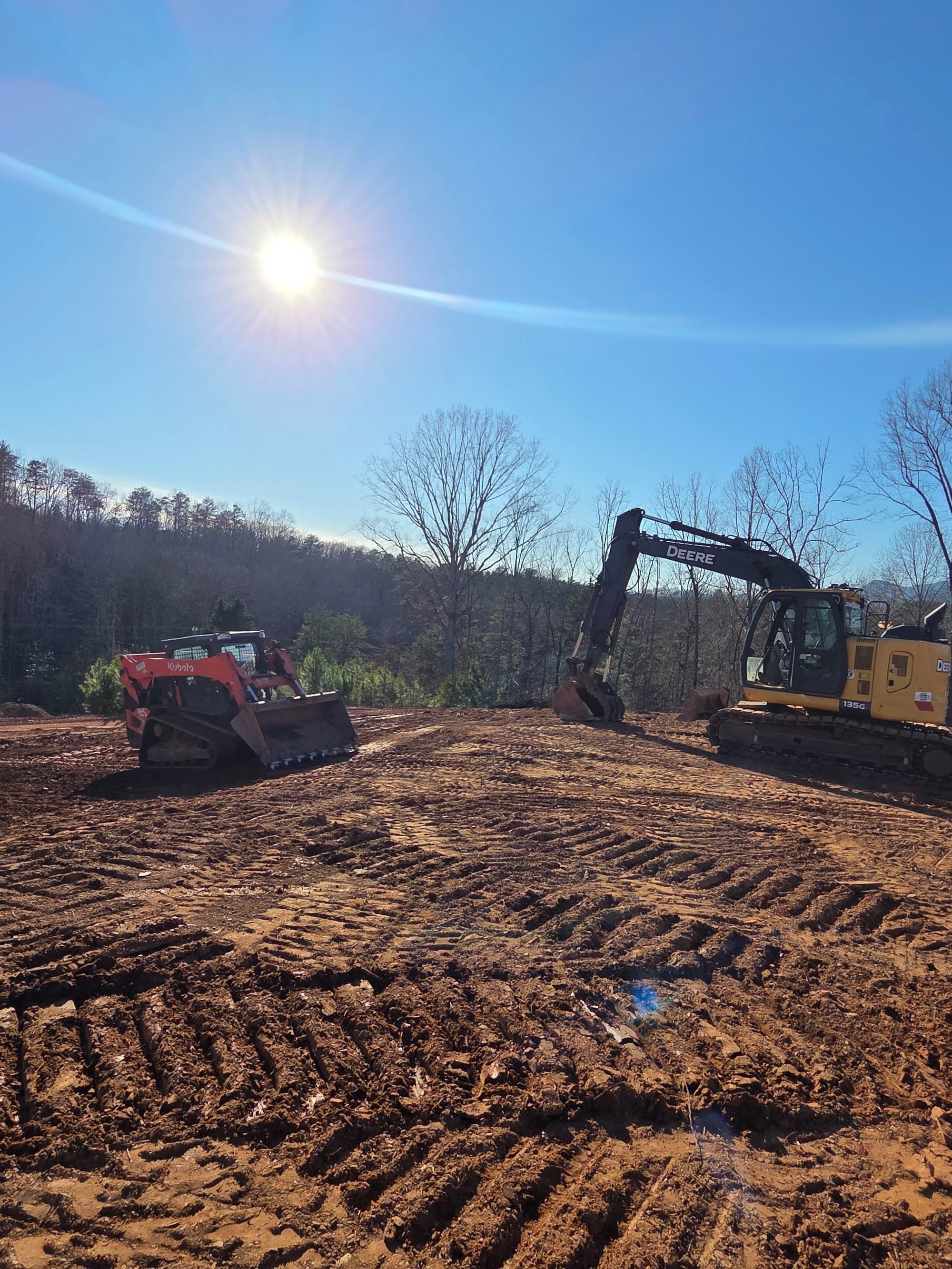 Track loader and excavator on a graded site