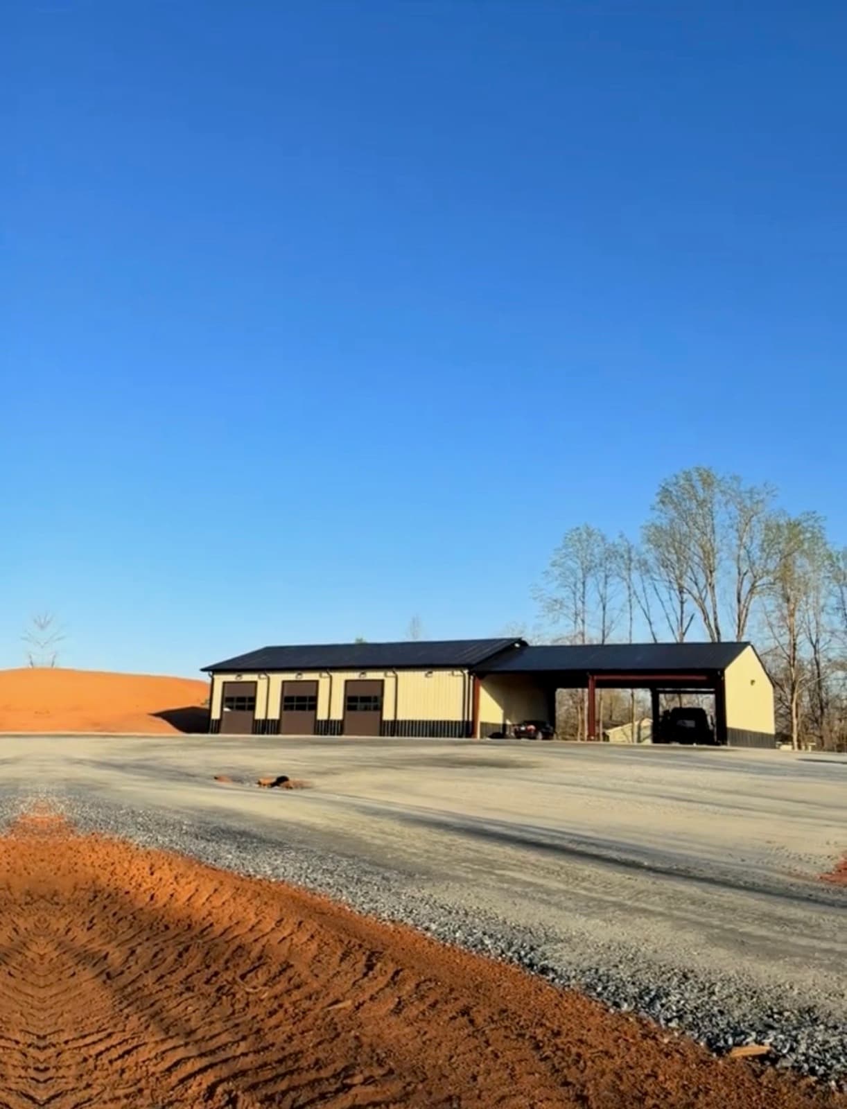 Finished gravel pad and graded site in front of a metal building
