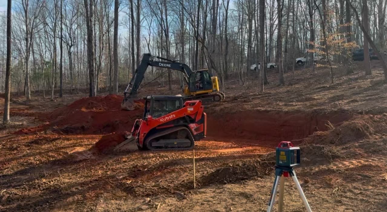 Track loader and excavator grading a site with a laser level