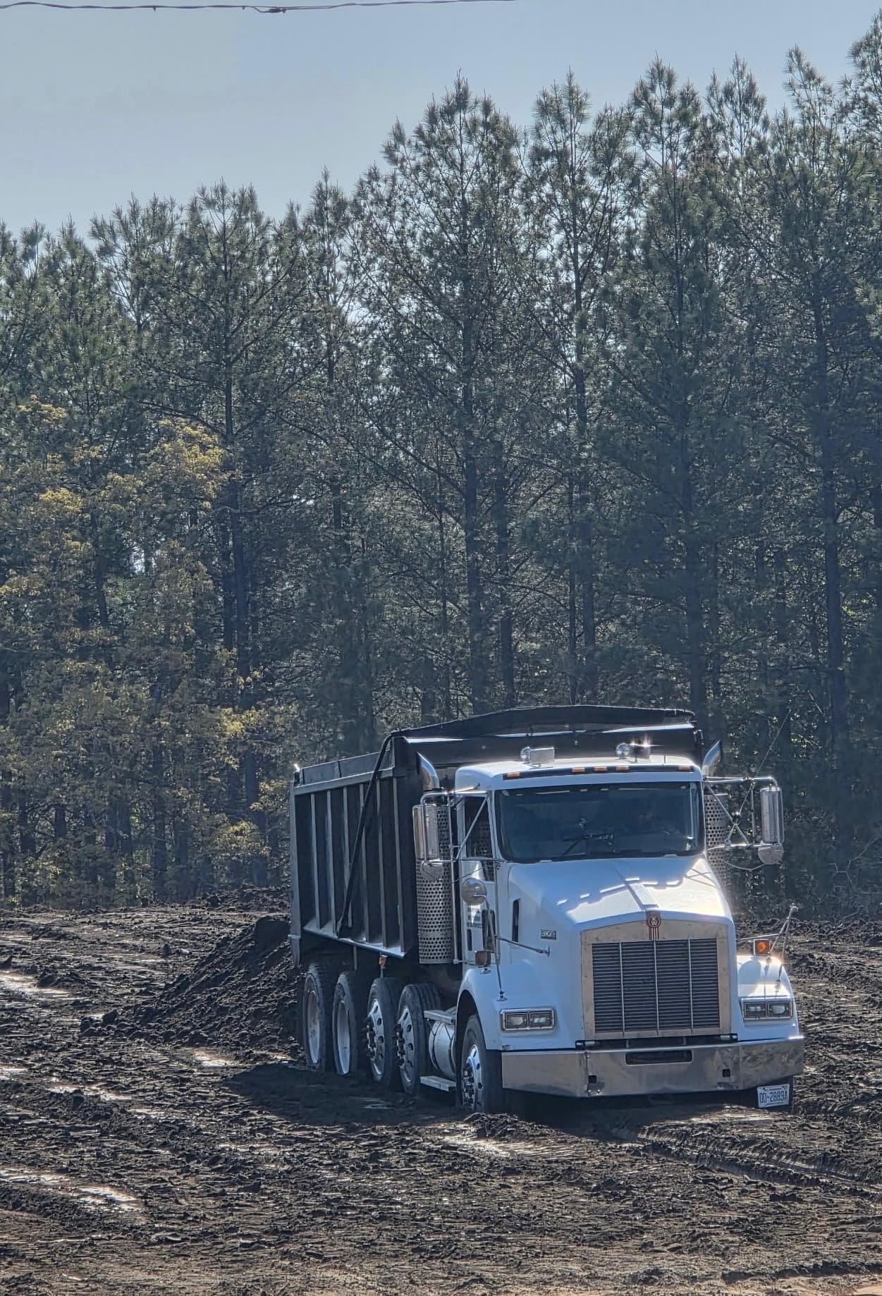 White Kenworth dump truck on a muddy job site