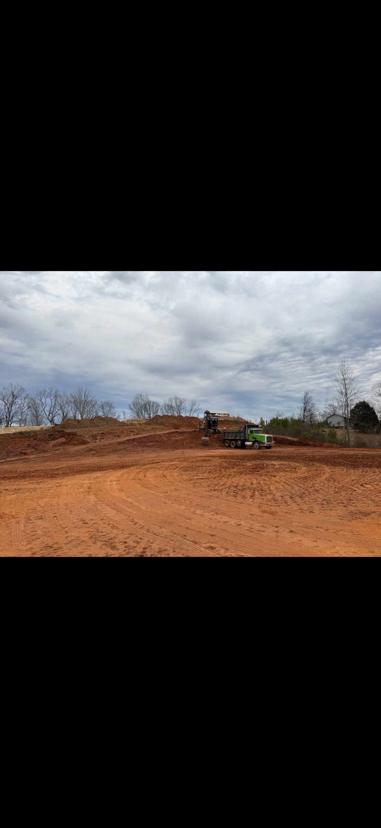 Excavator loading a dump truck on a large graded site